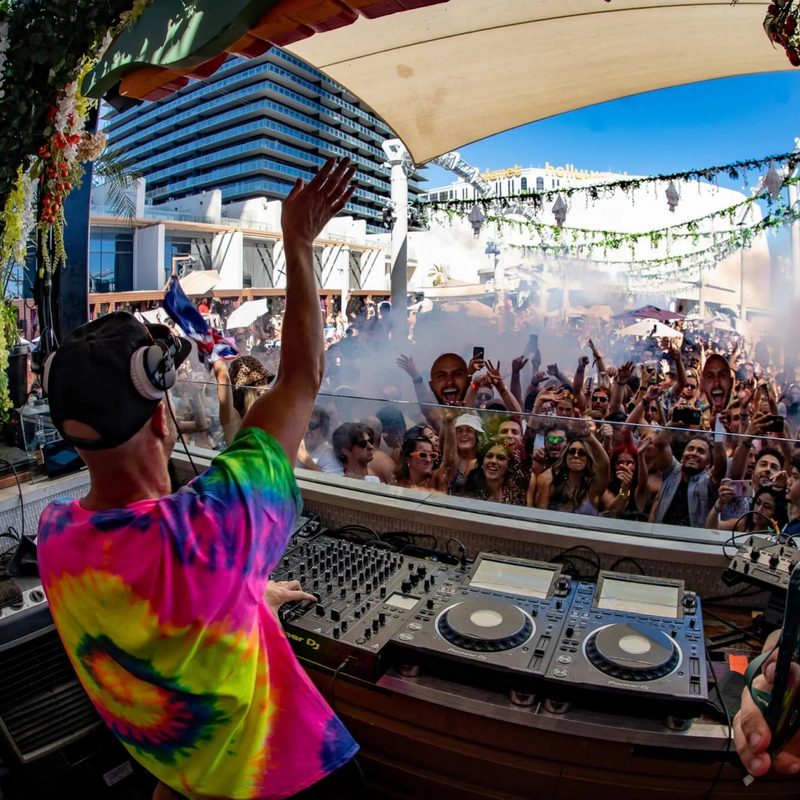 A DJ playing music to a crowd during the day at a Marquees Dome pool party