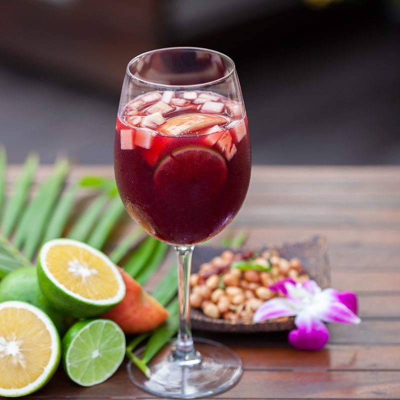 Glass of red wine with fruit and ice on table