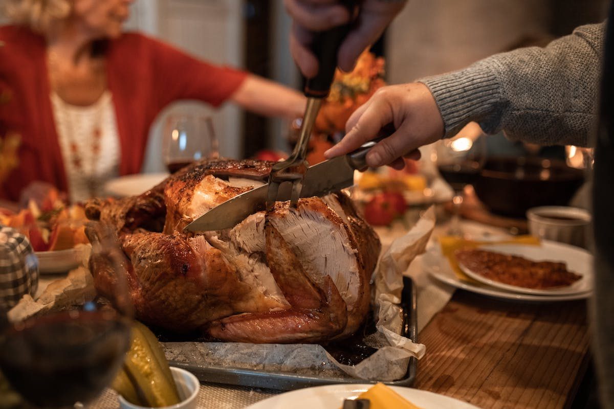 a person carving a turkey on thanksgiving