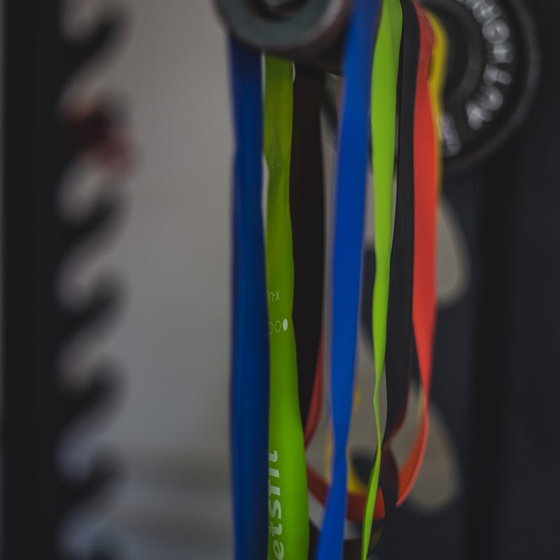 Colorful gym resistance bands hanging on weights in gym
