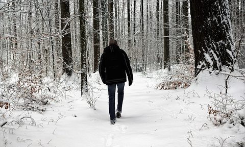 A man walking down a trail during the winter in the snow