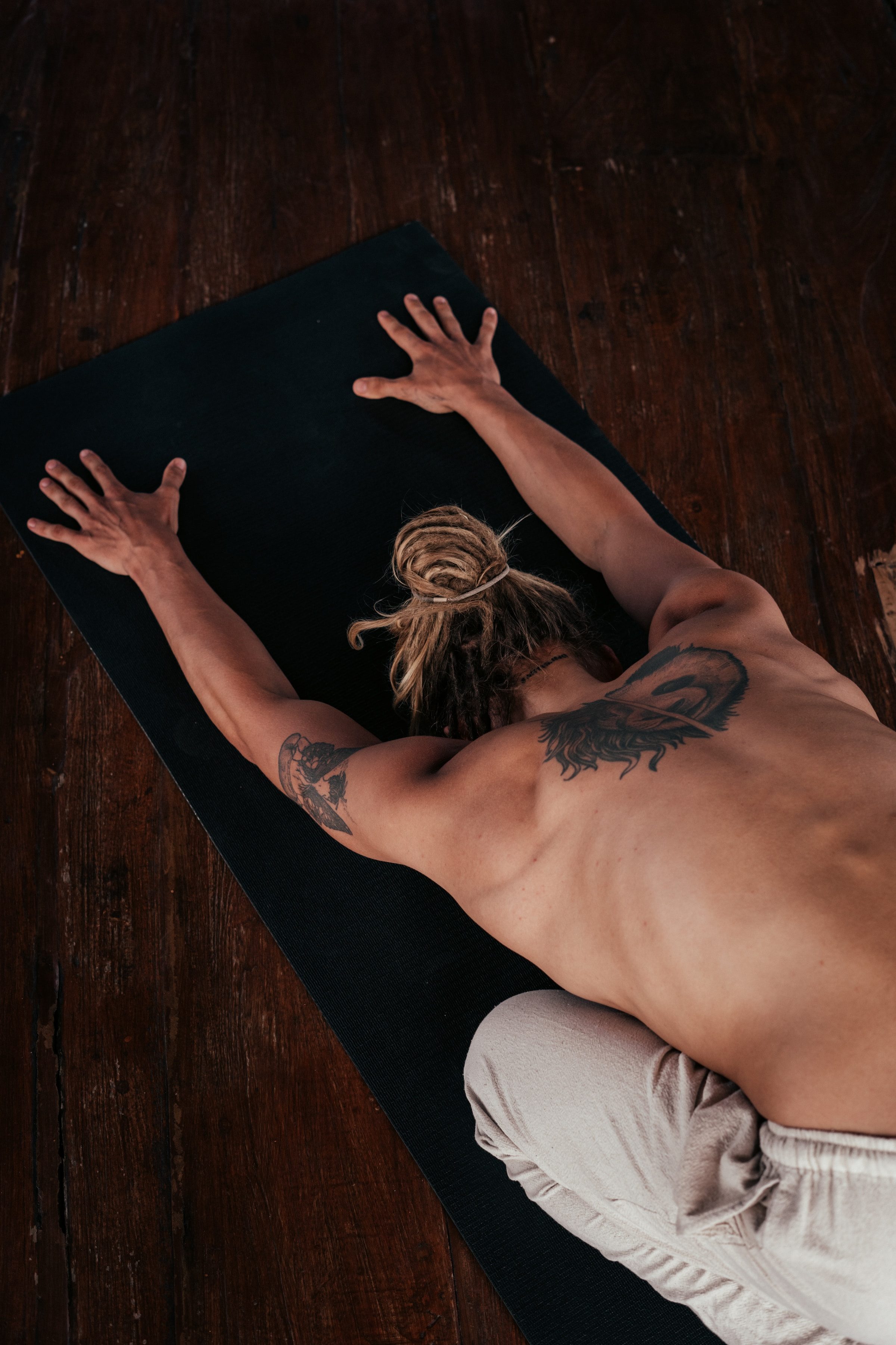 man stretching on floor on yoga mat with dreads