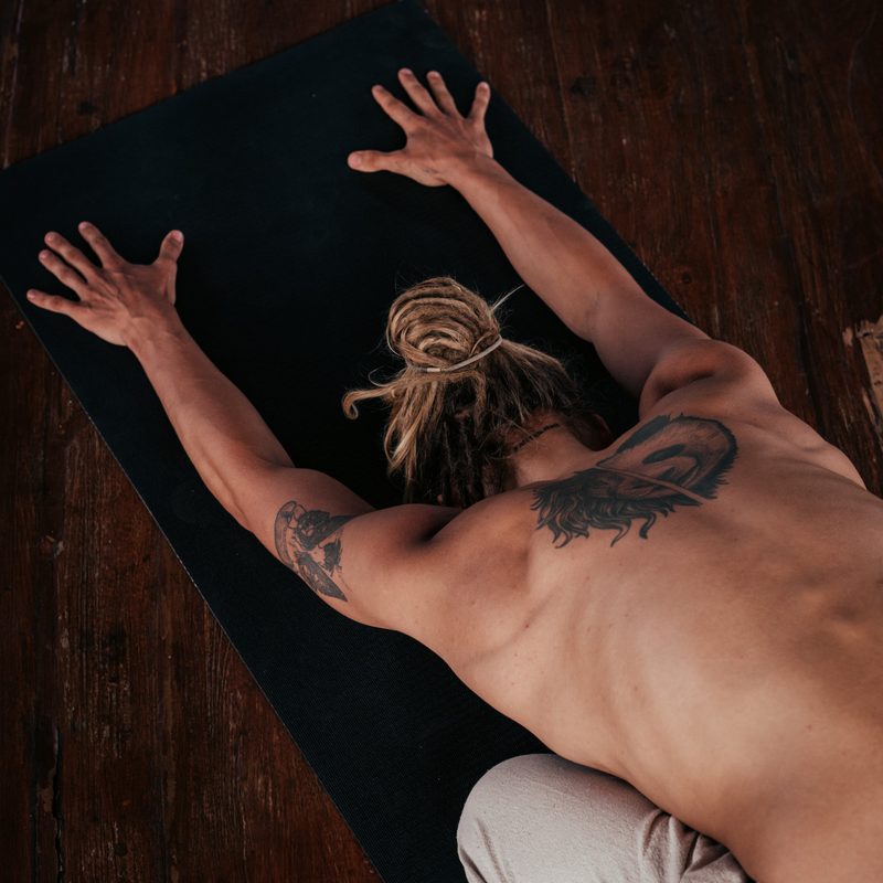 Man stretching on floor on yoga mat with dreads