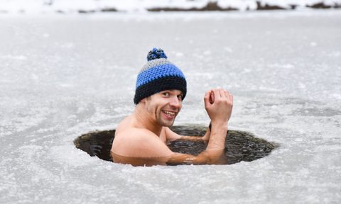 Man in ice water smiling with a beanie on his head