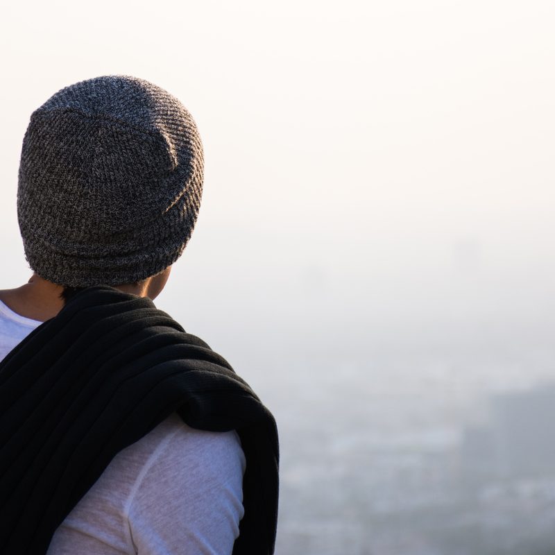 Man in a beanie looking over a city