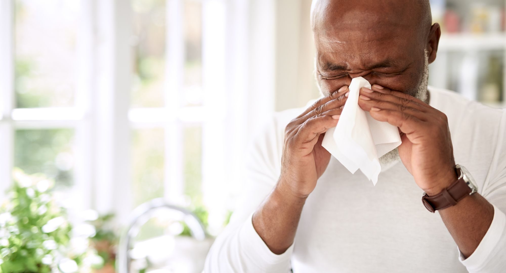 Man blowing his nose into a tissue