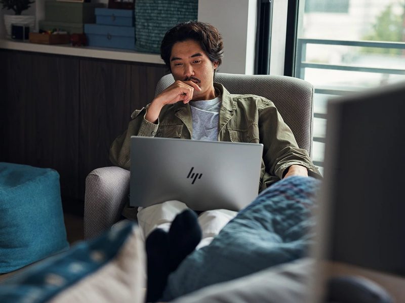 A man using an HP laptop in his home.