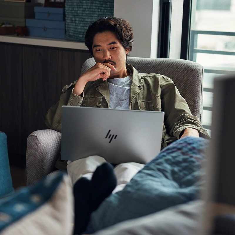 A man using an HP laptop in his home.