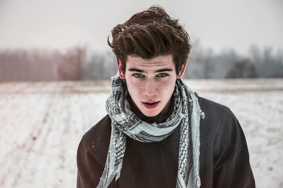 man standing in cold with scarf. and hair blowing in wind