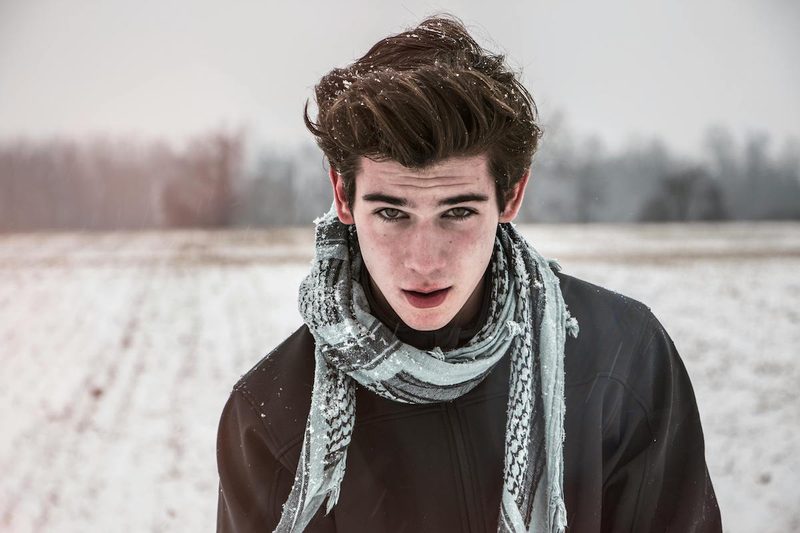 Man standing in cold with scarf. and hair blowing in wind