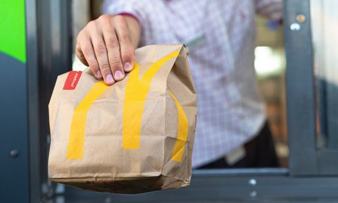 Hand with a paper bag through the window of McDonald's drive-thru