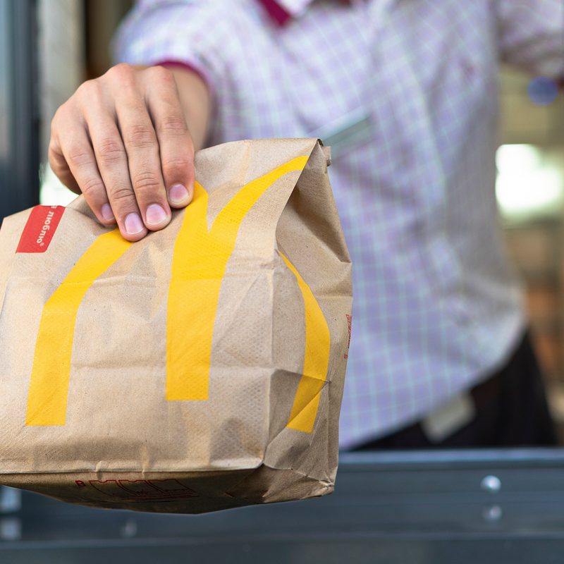 Hand with a paper bag through the window of McDonald's drive-thru