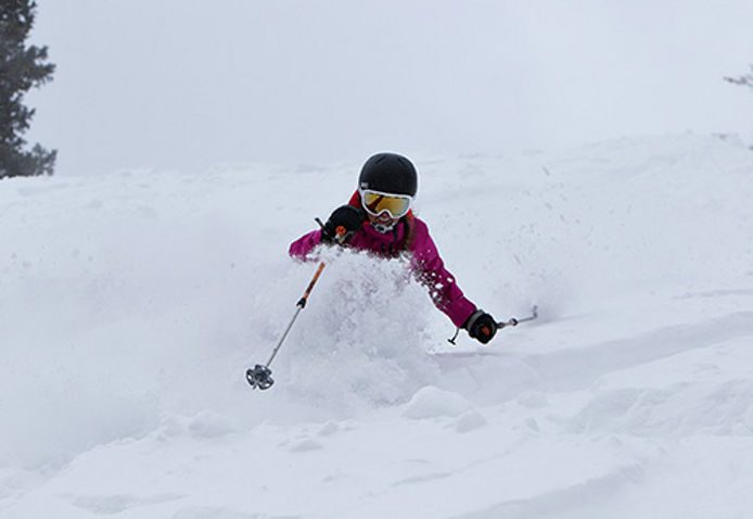 Female skier riding through powder in park city