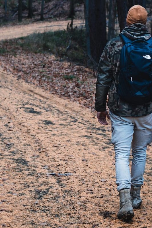 Man wearing hat walking through winding hiking trail