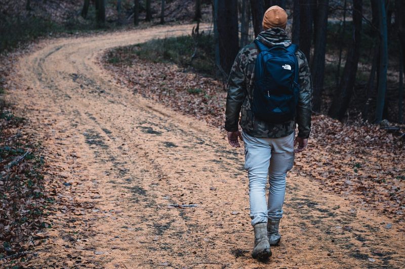 Man wearing hat walking through winding hiking trail