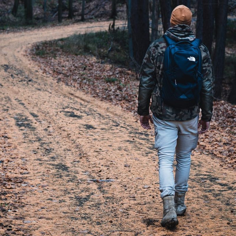 Man wearing hat walking through winding hiking trail
