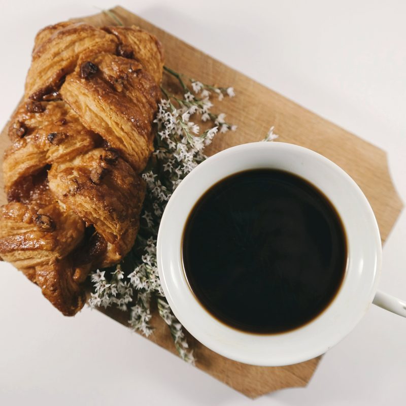 Black cup of coffee next to a pastry