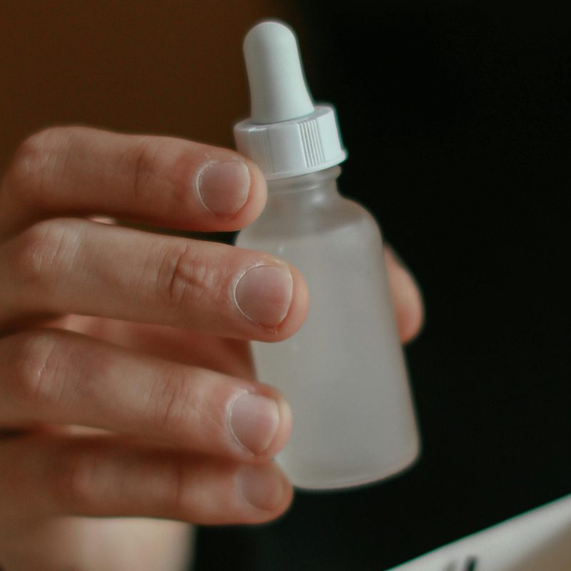 Man holding vial of face serum with dropper