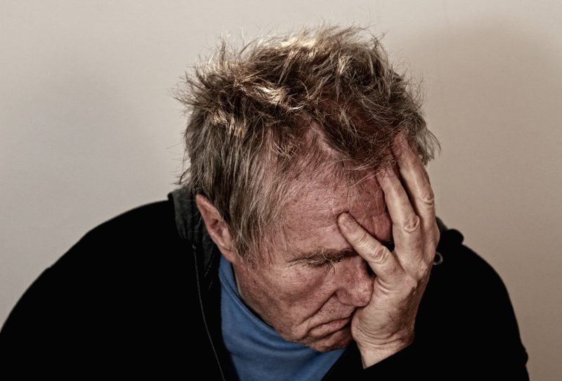 Man with frustrated expression and his face in the palm of his hand