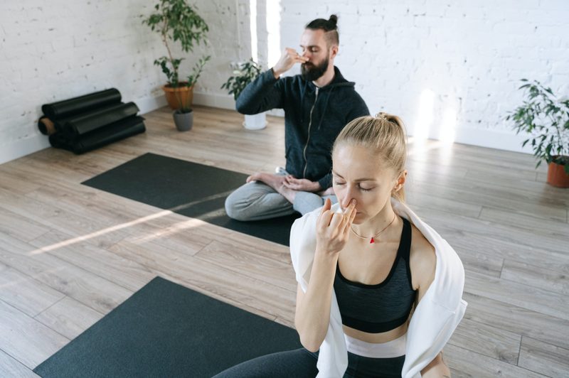 Two people sitting on yoga mats performing breathing exercises