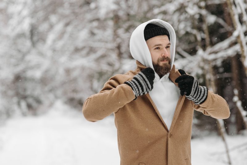 Man standing outside in snow wearing gloves