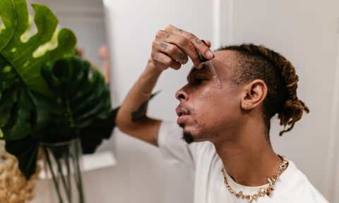 Man applying serum in mirror during skincare routine