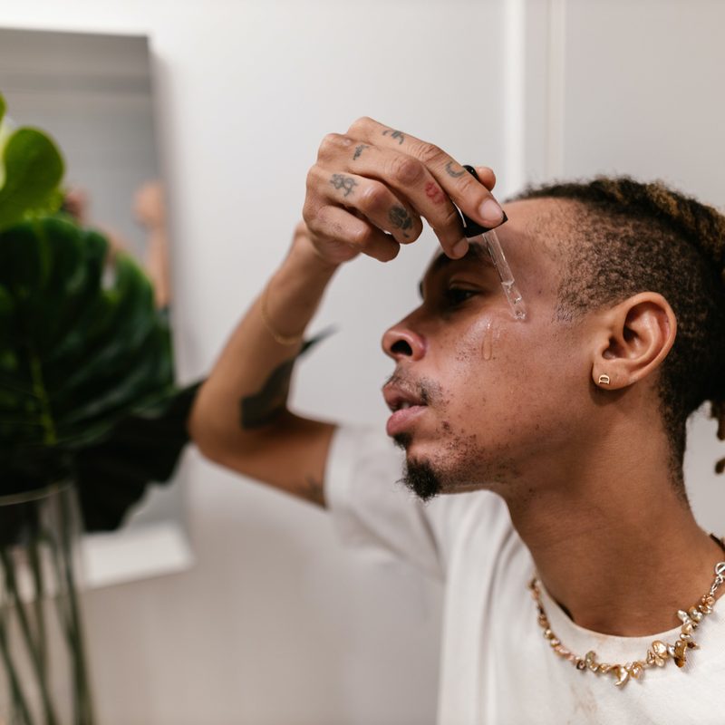Man applying serum in mirror during skincare routine