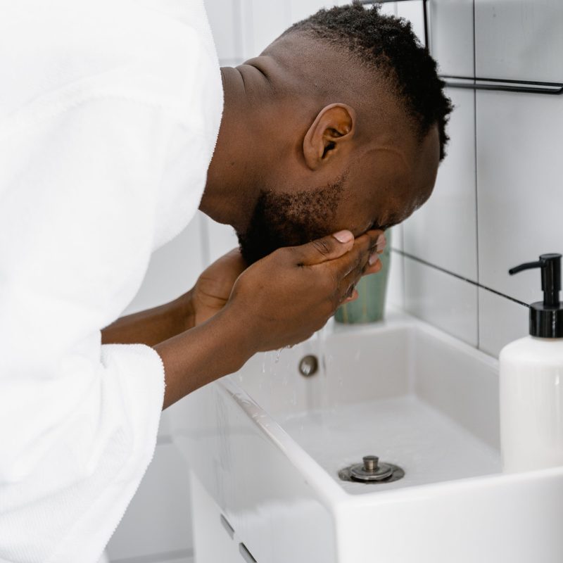 Man washing face in bathroom sink