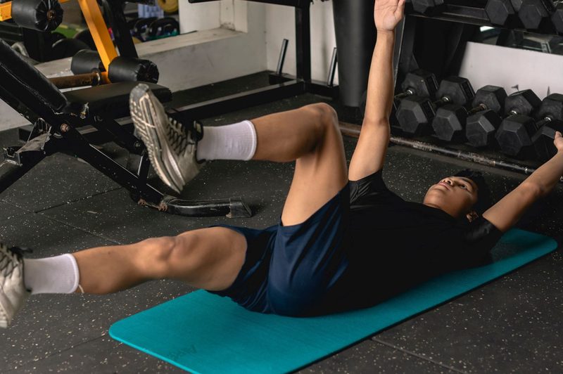 Man doing dead bug exercise on floor on blue mat
