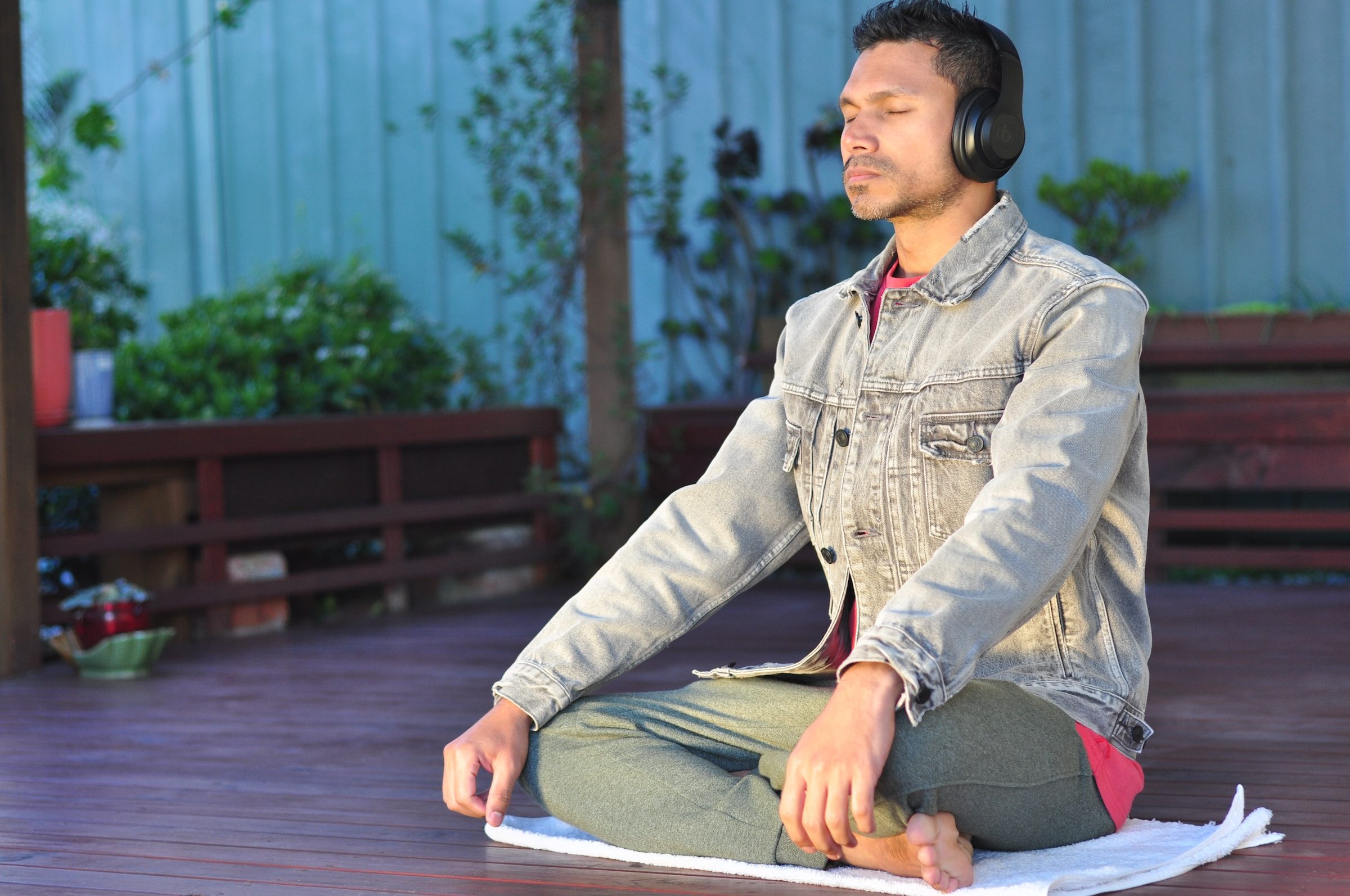 man sitting outside yoga pose listening to headphones