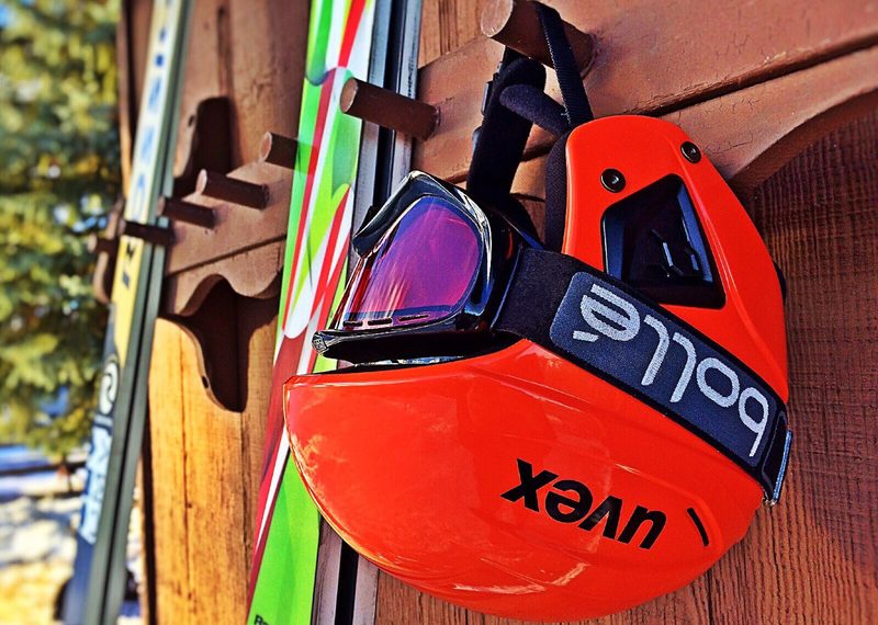 Ski helmet on a rack with goggles and skis in the background