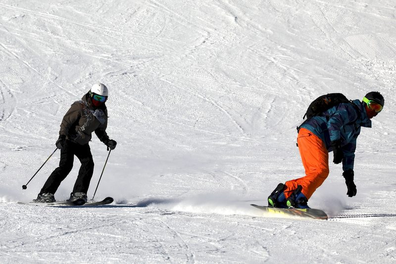 Skier and snowboarder riding downhill