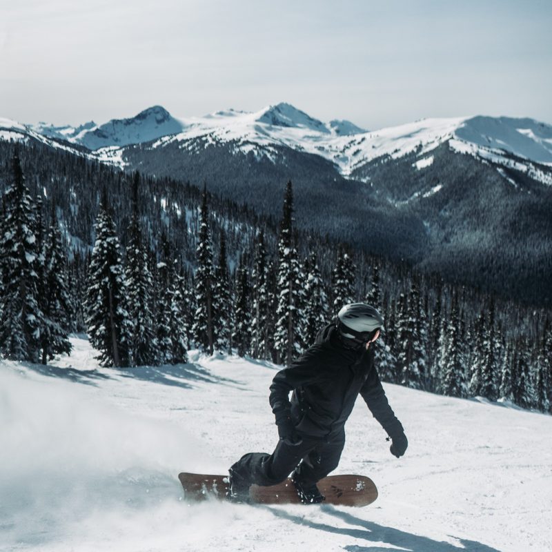 Snowboarder turning on groomers