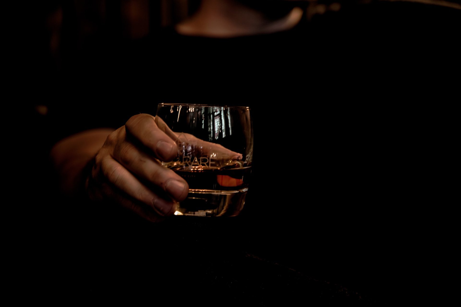 A person holding a glass of bourbon