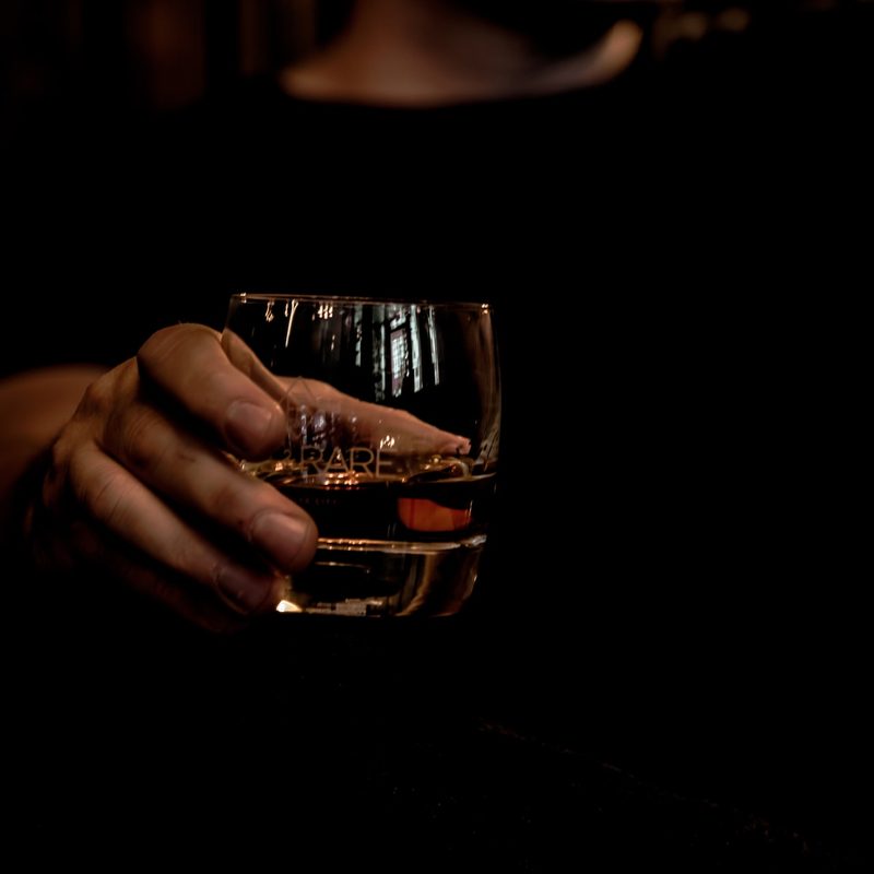 A person holding a glass of bourbon