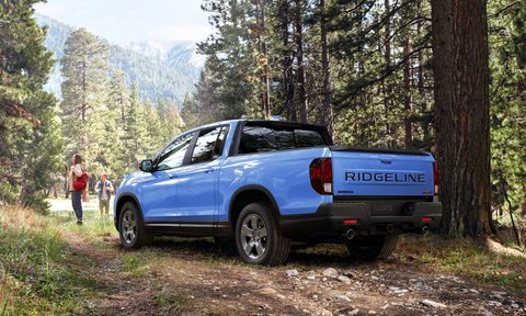2024 Honda Ridgeline TrailSport parked on a road in a forest with two people walking away.