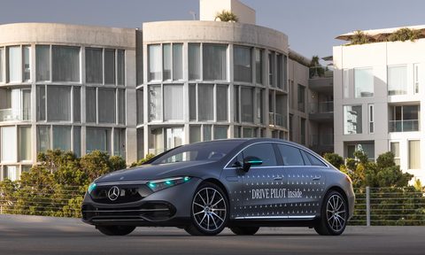 2024 Mercedes EQS equipped with Drive Pilot and turquoise lights left front three-quarter view in front of office buildings.