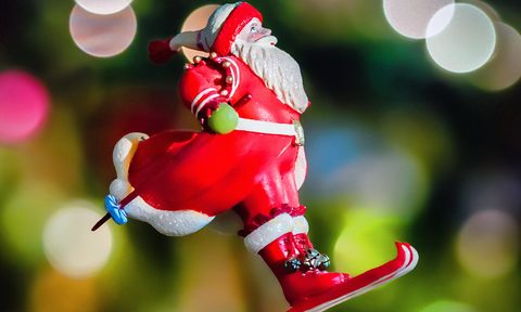 Santa Claus on skis in front of a Christmas Tree background