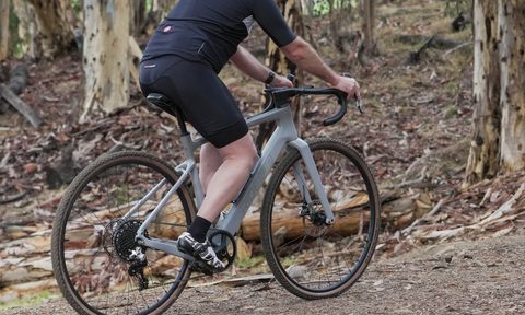 Ride1UP CF Racer1 with rider traveling up a dirt road.