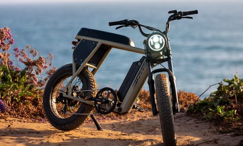 Right front three-quarter view of a Juiced Bikes Scrambler X2 parked on sand with ocean in the background.
