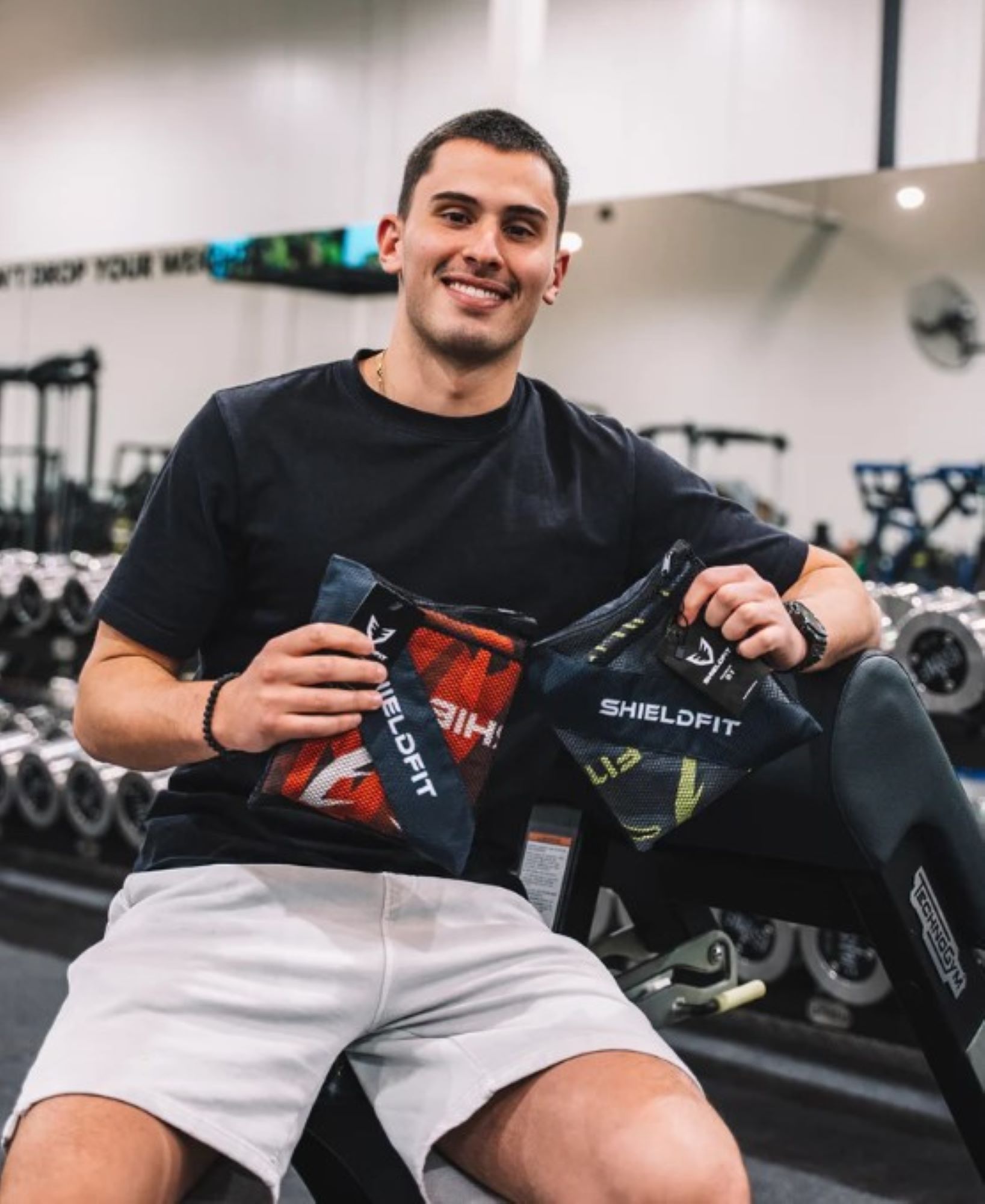 Shield Fit founder holding shield fit towels sitting in gym