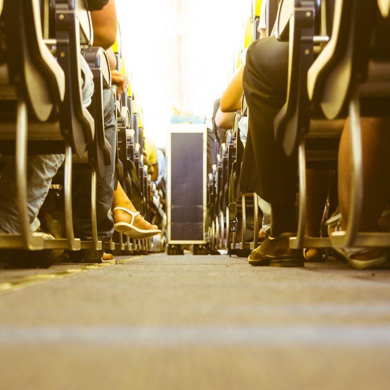 Airplane aisle with passengers feet on both sides