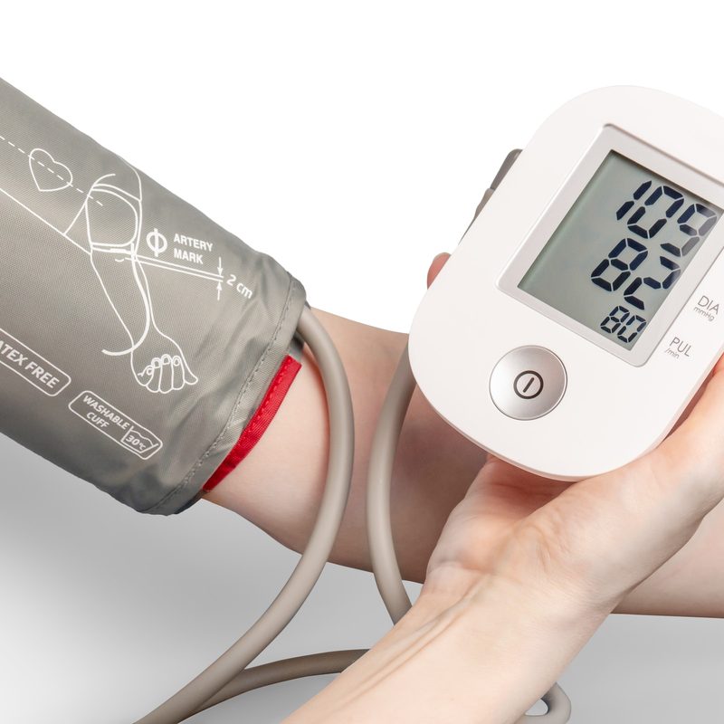 Someone close-up of arm using a blood pressure machine with white background