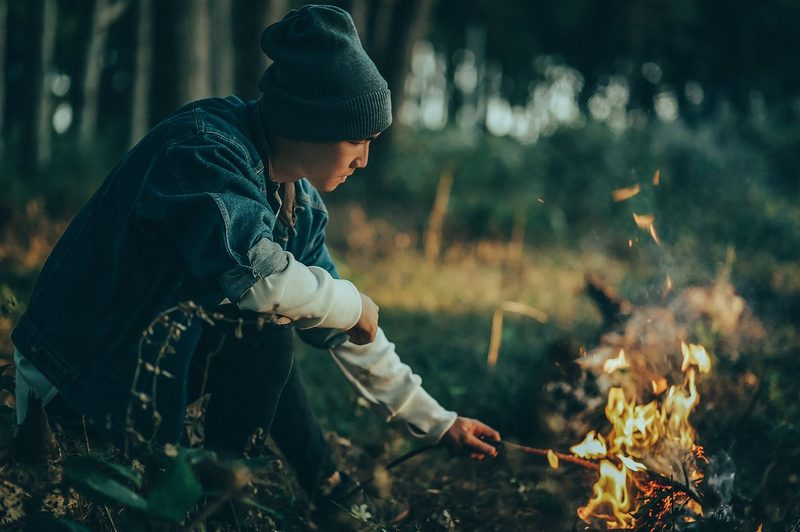 A man feeding a fire with wood in the forest