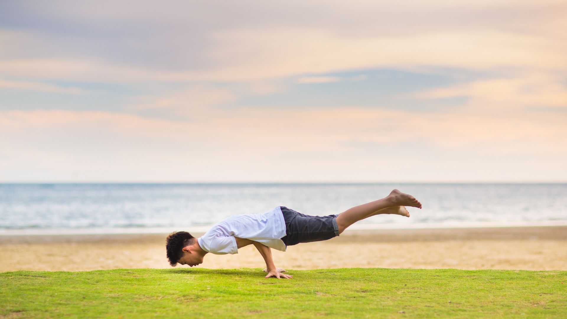 Teenager doing calisthenics exercise. Beach yoga