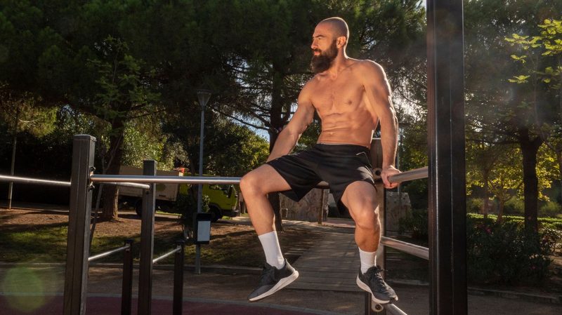 Sporty man with beard on calisthenics bars