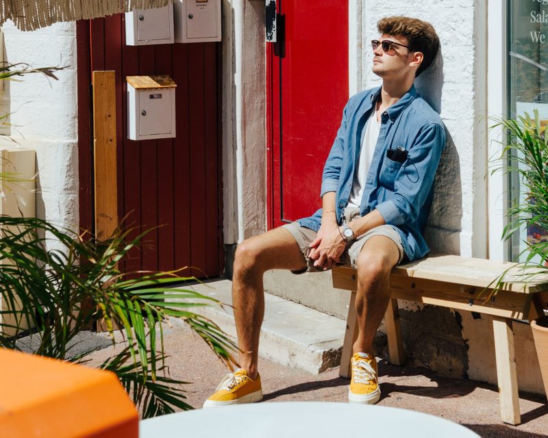 man sitting on bench in shorts and sunglasses