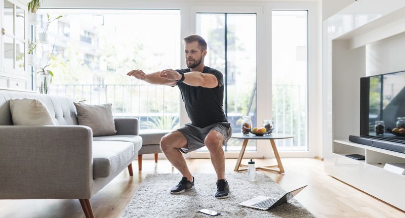 Man squatting with laptop workout