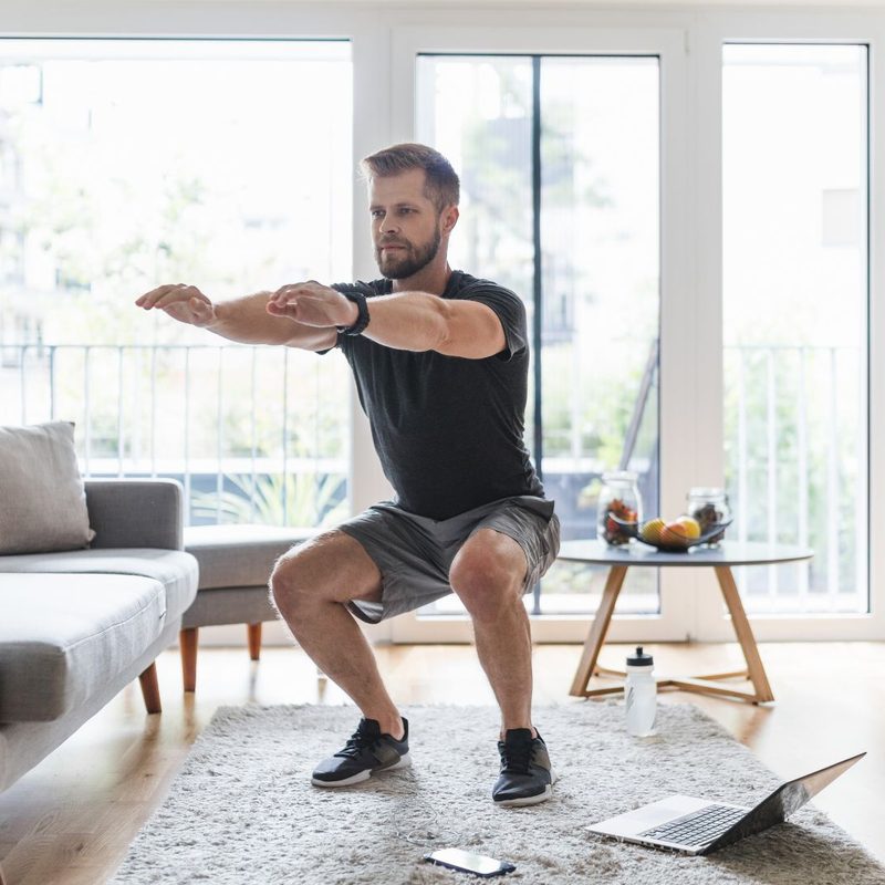 Man squatting with laptop workout