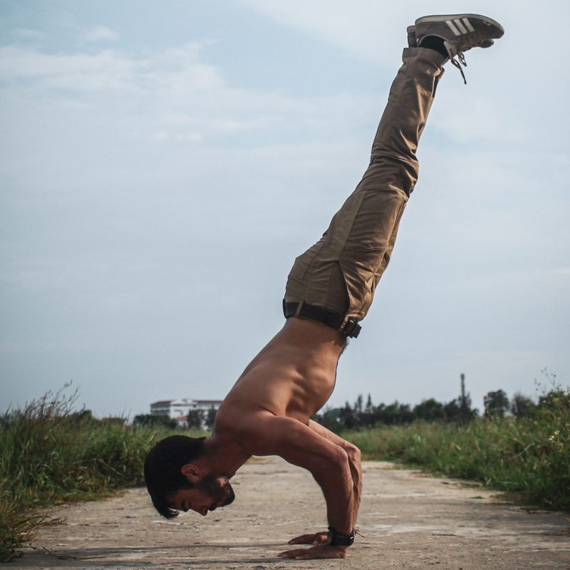 Man doing handstand outside no shirt just pants in nature
